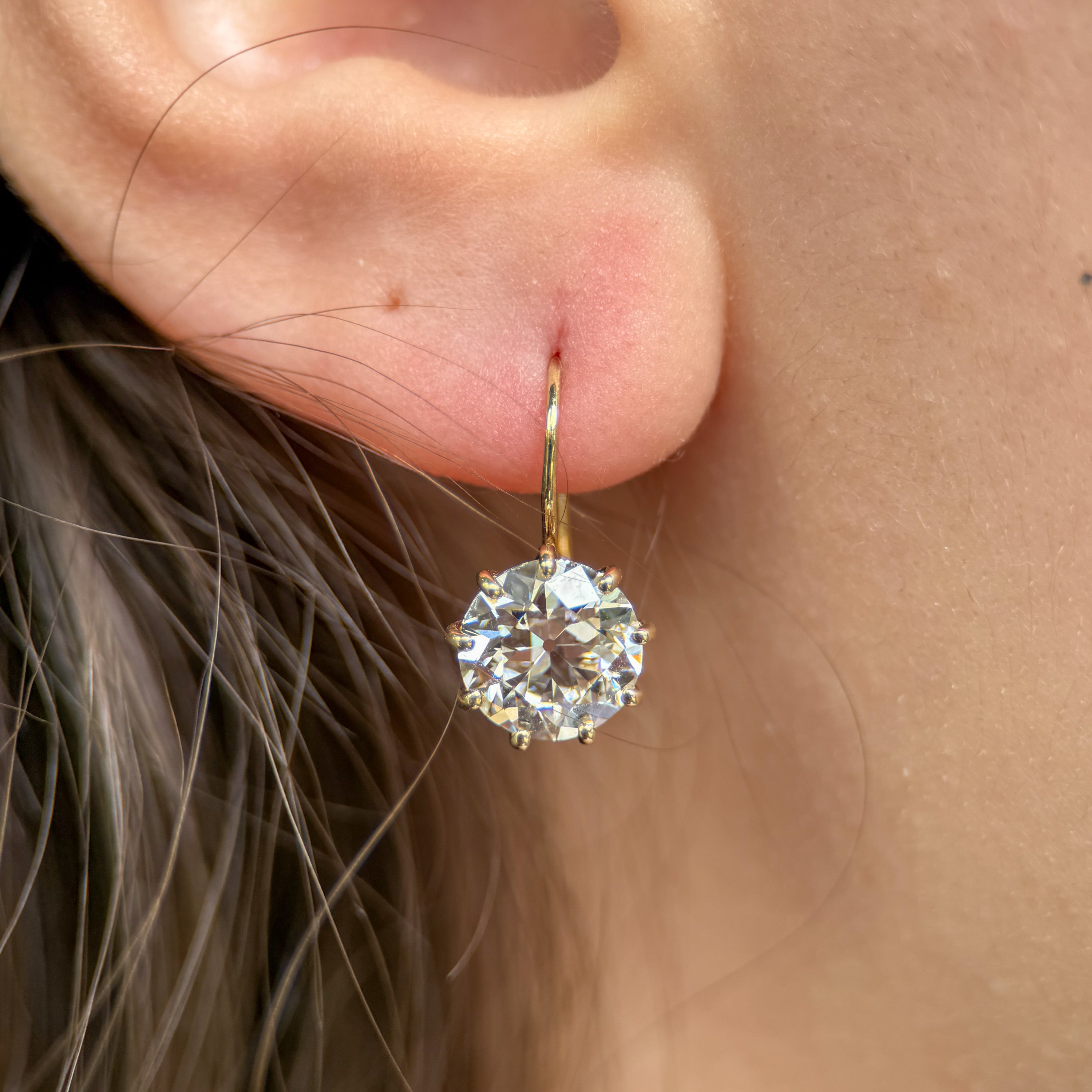 Gold earring with a large diamond worn by a person.